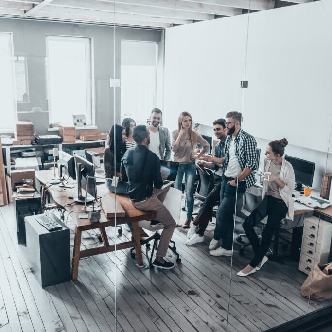 cooperation in action. full length top view of young business people in smart casual wear talking and smiling while having a brainstorm meeting in office